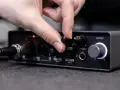 Dłoń reguluje pokrętło miksu na interfejsie audio, przygotowując wyjście liniowe do pracy.