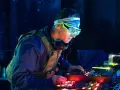 DJ w neonowych okularach tworzy pulsujący rytm acid house, zanurzając się w mroku klubu.