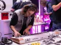 Młody mężczyzna w okularach i słuchawkach ćwiczy na keyboardzie Arturia. To część kursu produkcji muzycznej, gdzie można poznać tajniki tworzenia dźwięków.