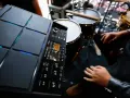 Nowoczesny sampler perkusyjny Roland SPD-SX PRO gotowy do tworzenia rytmów. W tle widoczne elementy zestawu perkusyjnego.