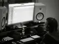 Producent muzyczny w słuchawkach tworzy beaty w studiu. Zastanawia się, czym się różni trap od rapu, analizując dźwięki na monitorze.