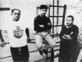 Trzech mężczyzn, pionierzy detroit techno, pozuje na tle ceglanej ściany.