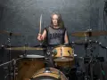 Kobieta z pałeczką w dłoni, gotowa do wygenerowania mocnych **drum beats** na zestawie perkusyjnym w studio.
