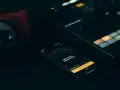 Czerwone słuchawki, kontroler Maschine i smartfon z aplikacją do tworzenia muzyki, gdzie widać koala sampler.