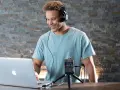 Mężczyzna w słuchawkach pracuje przy laptopie, obok niego stoi rejestrator dźwięku. Dba o wysoką głębię bitową nagrania.