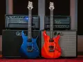 Dwie gitary, niebieska i pomarańczowa, stoją przed wzmacniaczami. Idealne guitar samples dla każdego muzyka.