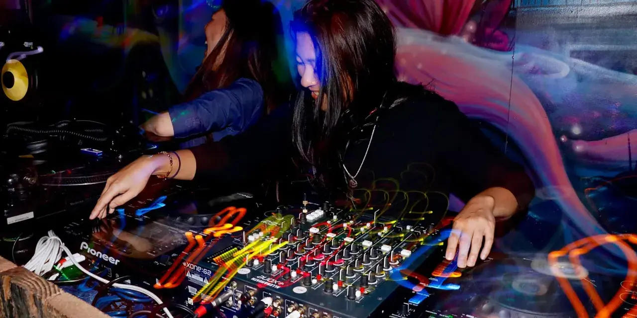 DJka miksuje energetyczne rytmy afro house w klubowej atmosferze. Kolorowe światła i dynamiczna muzyka tworzą niepowtarzalny klimat.