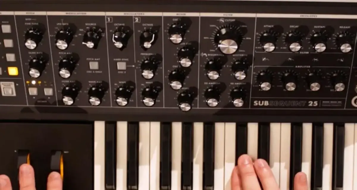 Dłonie grają na klawiaturze syntezatora Moog Subsequent 25, tworząc dźwięki.