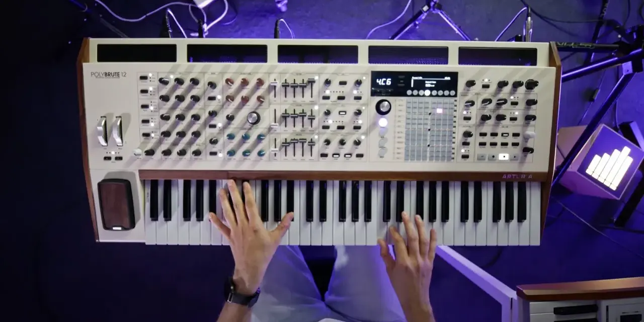 Ręce grają na syntezatorze Arturia PolyBrute 12. Widać pokrętła, suwaki i klawisze, tworząc bogate **music stems**.