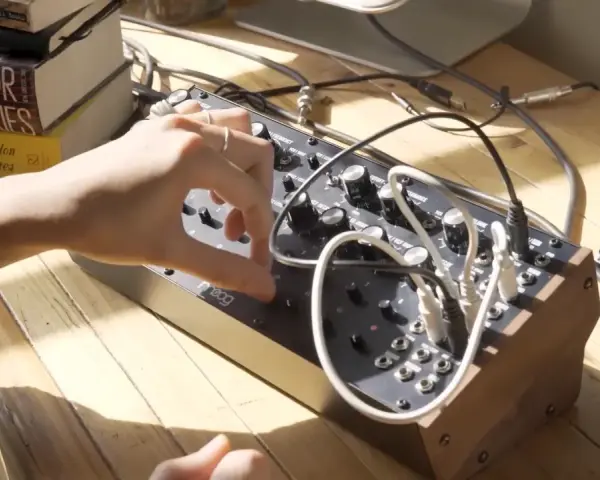 Ręka manipuluje pokrętłami na syntezatorze Moog DFAM, tworząc dźwięki.