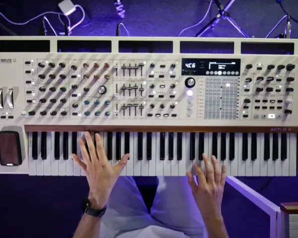Ręce grają na syntezatorze Arturia PolyBrute 12. Widać pokrętła, suwaki i klawisze, tworząc bogate **music stems**.