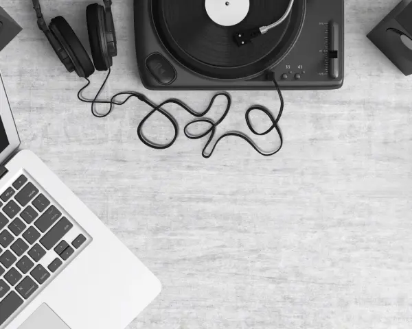 Laptop z programem do produkcji muzyki, gramofon, słuchawki i głośniki. Tworzenie utworu muzycznego z samplera.