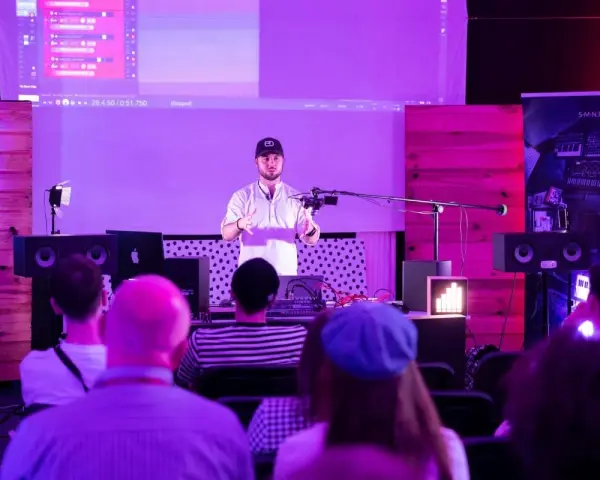 Prezentacja muzyczna z efektami, jak spring reverb. Mężczyzna mówi do mikrofonu, na ekranie widać program do produkcji muzyki.
