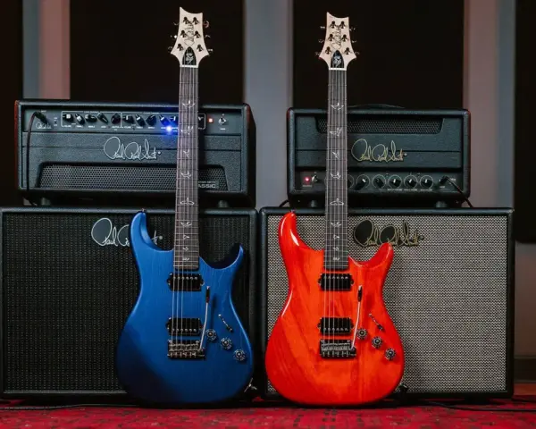 Dwie gitary, niebieska i pomarańczowa, stoją przed wzmacniaczami. Idealne guitar samples dla każdego muzyka.