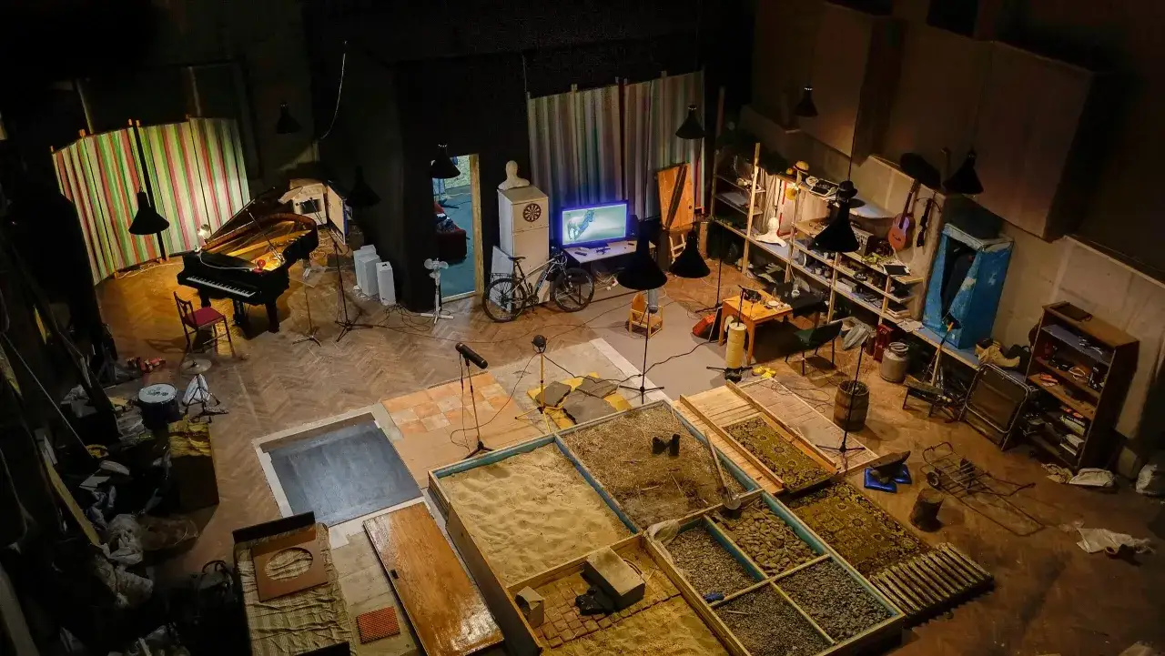 Studio nagraniowe z fortepianem, piaskiem, kamieniami i instrumentami. Przygotowania do nagrania unikalnych efektów dźwiękowych.