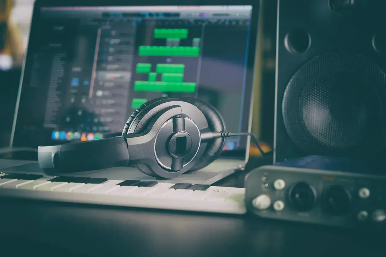 Słuchawki, klawiatura MIDI i interfejs audio na tle ekranu z programem do produkcji muzyki. Idealny zestaw do tworzenia dźwięków z najlepszymi pluginami.